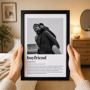 May include: A black framed print featuring a black and white photograph of a person giving another a piggyback ride, with the text boyfriend, noun, and a definition printed below the image in a clean, sans-serif font on a white background.