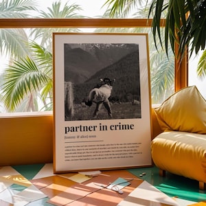 May include: A framed black and white print with the words "partner in crime" and a definition. The image shows a couple in a field. The print is in a wooden frame and is leaning against a window.