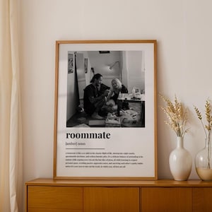 May include: A framed black and white photograph with the word "roommate" at the bottom. The photograph shows two people sitting on the floor. The definition of "roommate" is below the word.