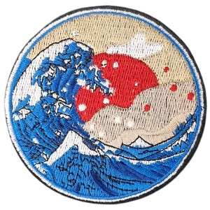 Puede incluir: Parche bordado con una ola azul y blanca con un sol rojo que sale detrás. La ola está estilizada para parecerse a la Gran Ola de Kanagawa, una famosa estampa japonesa en madera.