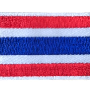 May include: Embroidered patch depicting the flag of Thailand. The rectangular patch has a white border and shows the Thai flag's design: five horizontal stripes in red, white, and blue. The top and bottom stripes are red.
