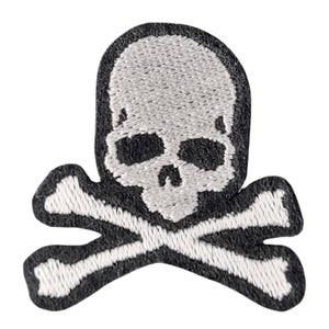 Puede incluir: Parche bordado con un diseño de calavera y huesos cruzados. La calavera es blanca con cuencas de ojos negras y una cavidad nasal, sobre un borde negro. Los huesos cruzados son blancos, sobre fondo blanco.