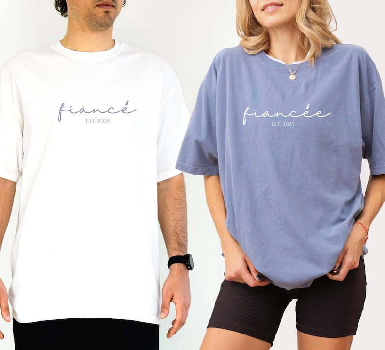 May include: White and blue t-shirts with the word "fianc&eacute;" and "fianc&eacute;e" printed in a script font. The text "EST. 2025" is below the words. The white shirt is worn by a person on the left, and the blue shirt is worn by a person on the right.