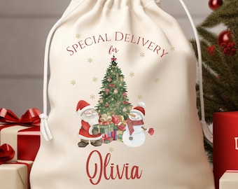 May include: A cream-colored drawstring gift bag with a Christmas theme. The bag features a watercolor illustration of Santa Claus, a snowman, and a decorated Christmas tree. The text "SPECIAL DELIVERY for Olivia" is printed in red.