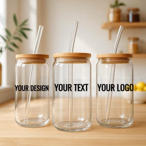 May include: Three clear glass beverage containers with wooden lids and clear straws. Each jar has black text: "YOUR DESIGN", "YOUR TEXT", and "YOUR LOGO". The jars are on a wooden surface.