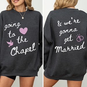 May include: Dark gray sweatshirt with white script text on the front that reads "going to the Chapel" with a pink heart and a pink dove. The back of the sweatshirt says "& we're gonna get Married" with two pink wedding rings.