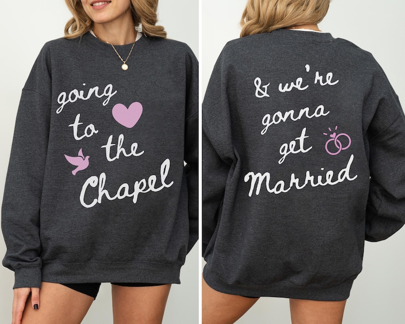 May include: Dark gray sweatshirt with white script text on the front that reads "going to the Chapel" with a pink heart and a pink dove. The back of the sweatshirt says "& we're gonna get Married" with two pink wedding rings.