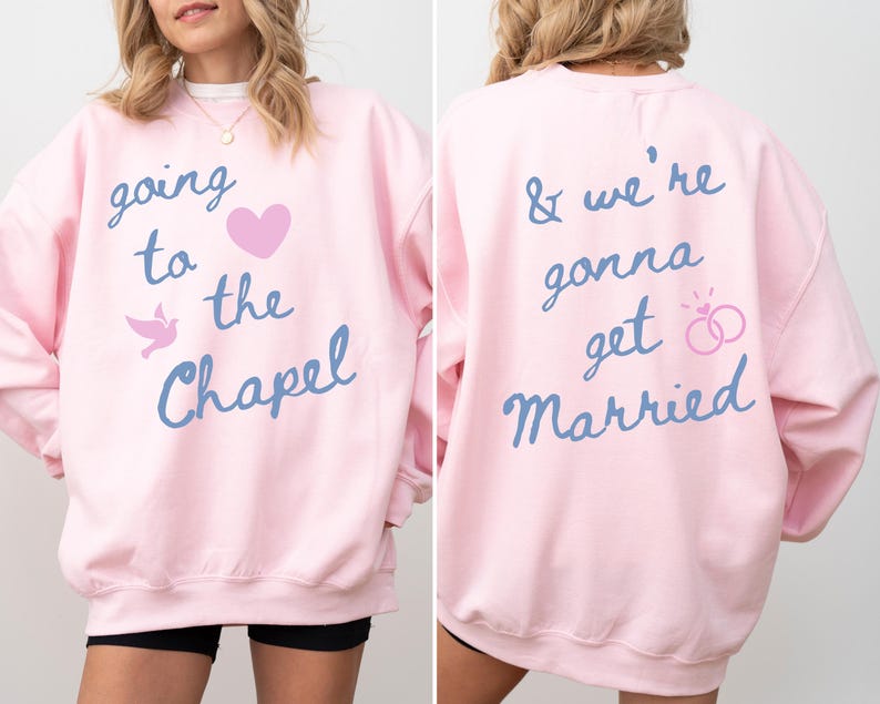 May include: A light pink sweatshirt with the text "going to the Chapel" and "& we're gonna get Married" in blue script. The front features a pink heart and a dove graphic. The back has a ring graphic.