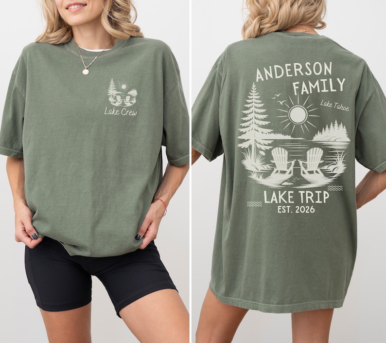 May include: An olive green short-sleeve t-shirt featuring a small graphic on the front left chest with two chairs, trees, and the text Lake Crew. The back displays a large graphic of two chairs by a lake, trees, sun, and text Anderson Family Lake Trip Est. 2026.