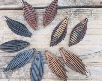 May include: A set of eight leather earrings in various colours and patterns, including brown, black, and tan. The earrings are shaped like feathers and have a fringed design.