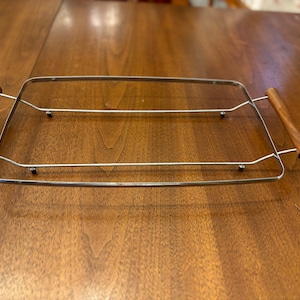 May include: A silver serving tray with two wooden handles. The tray has a rectangular shape and is made of metal.