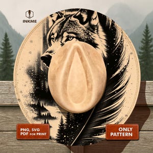 May include: A tan cowboy hat with a detailed wolf illustration on the brim. The artwork features a black and white wolf, pine trees, and a feather design. The hat has a light brown crown and a wide brim.