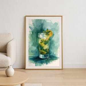 May include: Watercolor print of a refreshing mojito cocktail in a tall glass. The drink features ice, mint leaves, and a lemon slice. The background is a teal and green watercolor wash, framed in gold.