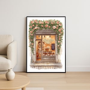 Könnte beinhalten: Ein gerahmter Aquarelldruck einer Schokoladenladen-Fassade, geschmückt mit rosa Rosen und grünem Laub. Das Geschäft mit dem Namen "Chocolaire Chocolates" zeigt eine Auslage mit Schokoladengläsern und eine Tafel-Speisekarte. Der Name des Geschäfts steht über dem Eingang.