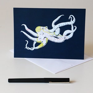 May include: A navy blue card with a white octopus made from a map. The octopus is outlined in black and has yellow accents.