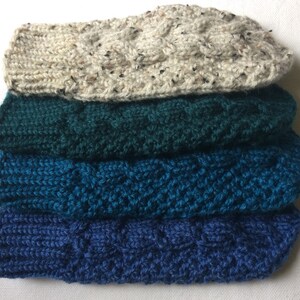 K&ouml;nnte beinhalten: Vier Paar gestrickte Socken in verschiedenen Blaut&ouml;nen und Gr&uuml;nt&ouml;nen. Die Socken sind &uuml;bereinander gestapelt, wobei die oberste Socke eine hellbeige Farbe hat.