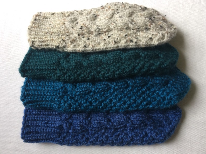 K&ouml;nnte beinhalten: Vier Paar gestrickte Socken in verschiedenen Blaut&ouml;nen und Gr&uuml;nt&ouml;nen. Die Socken sind &uuml;bereinander gestapelt, wobei die oberste Socke eine hellbeige Farbe hat.