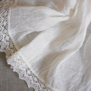 May include: White linen fabric with a delicate lace trim. The fabric is soft and flowing, with a slightly textured surface.