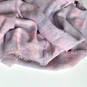 Puede incluir: Bufanda suave y drapeada en tonos lavanda y rosa. La tela tiene un efecto de acuarela con bordes deshilachados. La bufanda está hecha de un material ligero, perfecto para añadir un toque de color y textura a cualquier atuendo. Mide unos 150 cm.