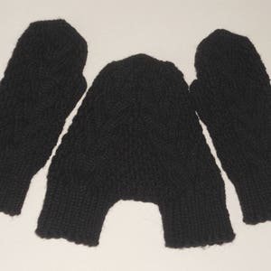K&ouml;nnte beinhalten: Ein Paar schwarze Strickhandschuhe mit einem Zopfmuster.
