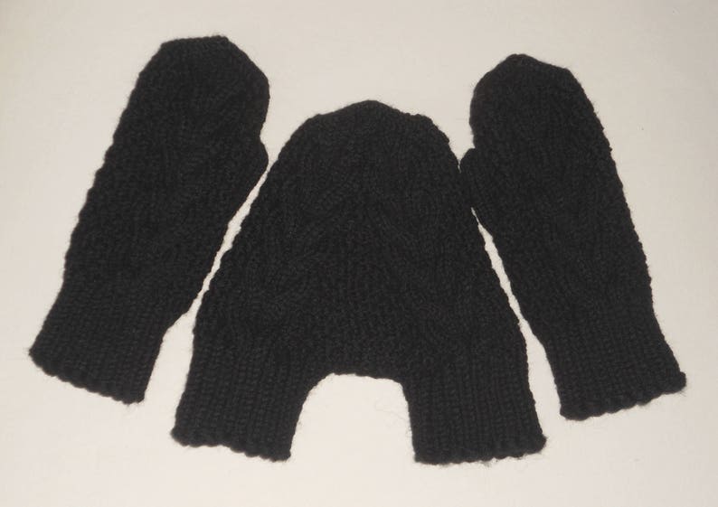 K&ouml;nnte beinhalten: Ein Paar schwarze Strickhandschuhe mit einem Zopfmuster.
