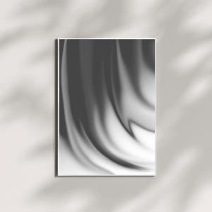 Puede incluir: Una impresión artística abstracta enmarcada con un diseño en escala de grises y fluido. La obra de arte presenta una mezcla de tonos oscuros y claros, creando un patrón suave y ondulado. La impresión se muestra en una pared blanca con sombras.