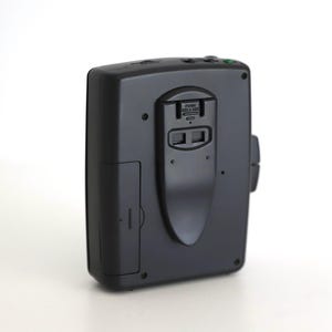 Puede incluir: Reproductor de casetes negro con micr&oacute;fono incorporado y conector para auriculares. El reproductor tiene un peque&ntilde;o bot&oacute;n verde en la parte superior.