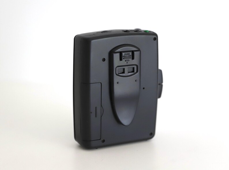 Puede incluir: Reproductor de casetes negro con micr&oacute;fono incorporado y conector para auriculares. El reproductor tiene un peque&ntilde;o bot&oacute;n verde en la parte superior.