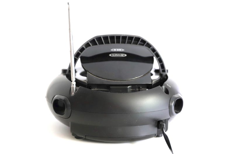 May include: Black portable CD player with a silver antenna and a handle. The CD player has a round shape with two speaker holes on the sides. The CD player is on a white background.