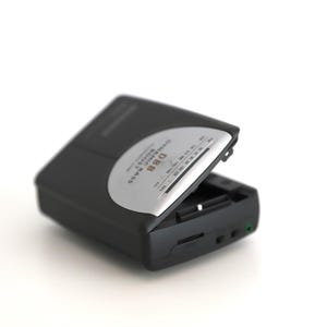 Puede incluir: Un reproductor de casetes negro y plateado con el texto "Digital Stereo Radio" y "DBB" impreso en la parte delantera.
