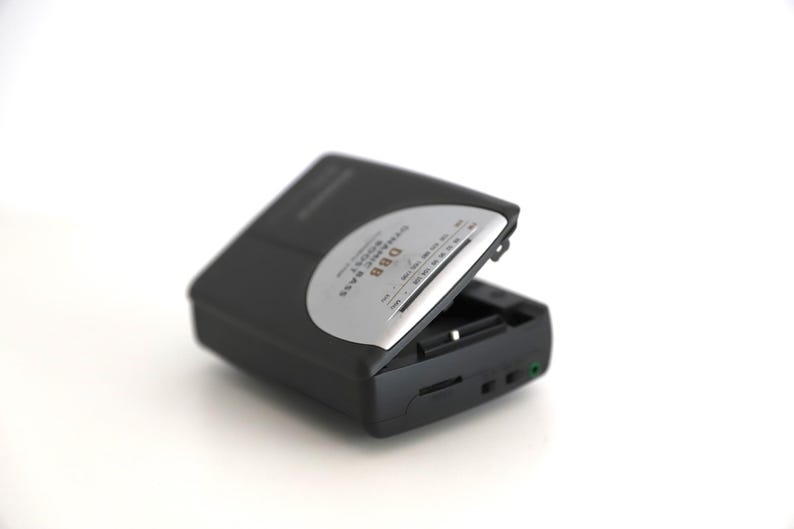 Puede incluir: Un reproductor de casetes negro y plateado con el texto "Digital Stereo Radio" y "DBB" impreso en la parte delantera.