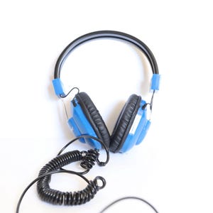 May include: Blue and black over-ear headphones with a coiled black cord. The headphones have a black headband and blue ear cups. The ear cups are connected to the headband with blue plastic pieces.