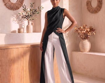 May include: A sleeveless black high-neck tunic with a draped front and a long, open-front split design, paired with crisp white wide-leg trousers. The ensemble features a structured bodice and flowing fabric that extends to the floor.