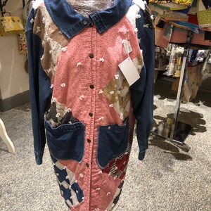 May include: A long-sleeved jacket featuring a patchwork design with pink, blue, and patterned fabric panels. It has a denim collar, denim sleeves, and two denim patch pockets on the front. The jacket closes with metal buttons and includes a white tag.