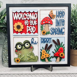 May include: A handmade wooden sign with the text "Welcome" in a handwritten style. The sign is painted white with a distressed finish and features a small, decorative heart. It is designed for indoor or outdoor use.
