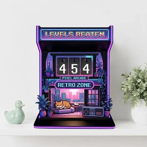 May include: A black and purple pixel arcade-style decorative piece with the text "LEVELS BEATEN" and "RETRO ZONE". The display shows the number 454. A pixelated cat rests on a couch inside the arcade scene. The arcade is decorated with plants.