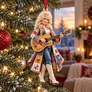 Könnte beinhalten: Ein Weihnachtsbaumschmuck in Form einer blonden Figur mit voluminösem Haar, die einen langen, mehrfarbigen Patchwork-Mantel mit Blumenstickerei, eine blaue Jeans und weiße Stiefel trägt und eine hölzerne Akustikgitarre hält.