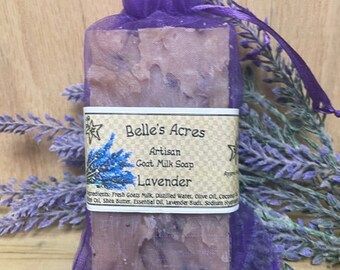 May include: A rectangular bar of lavender goat milk soap encased in a purple organza drawstring bag. The soap features a paper label with the text Belle's Acres, Artisan Goat Milk Soap, and Lavender, along with a graphic of lavender sprigs.