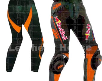 May include: Black and orange motorcycle pants with knee and hip protection. The pants feature orange accents and the KTM and Red Bull logos. The pants are designed for motorcycle riding and racing.