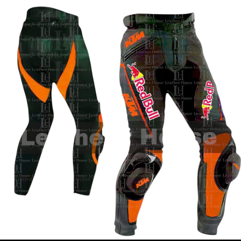 Op de afbeelding: Zwarte en oranje motorbroek met knie- en heupbescherming. De broek heeft oranje accenten en de KTM- en Red Bull-logo's. Ontworpen voor motorrijden en racen.
