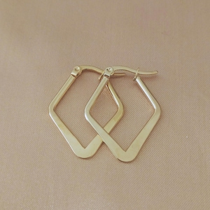 Op de afbeelding: Een paar goudkleurige, ruitvormige oorringen. De oorbellen hebben een geometrisch ontwerp en een eenvoudige, elegante stijl. De oorbellen worden gepresenteerd op een neutrale achtergrond.