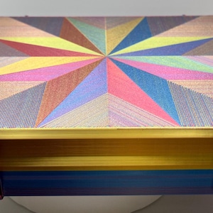 May include: A colorful, geometric patterned box with a gold trim and blue base. The box has two latches on the front.