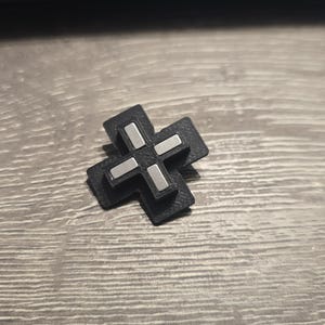 May include: A black cross-shaped object with a silver plus sign in the center.