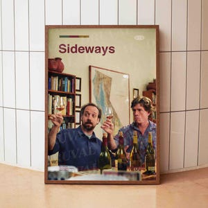 Puede incluir: Póster enmarcado con el título de la película "Sideways". La imagen muestra a dos hombres sosteniendo copas de vino, con botellas de vino y una estantería de fondo. El póster está en un marco de madera y muestra un mapa en la pared.