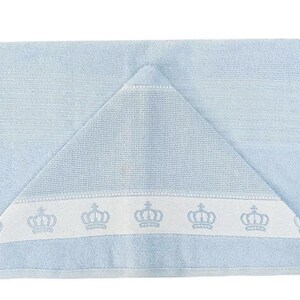 Op de afbeelding: Een lichtblauwe badcape met een witte rand en een rij geborduurde kronen.