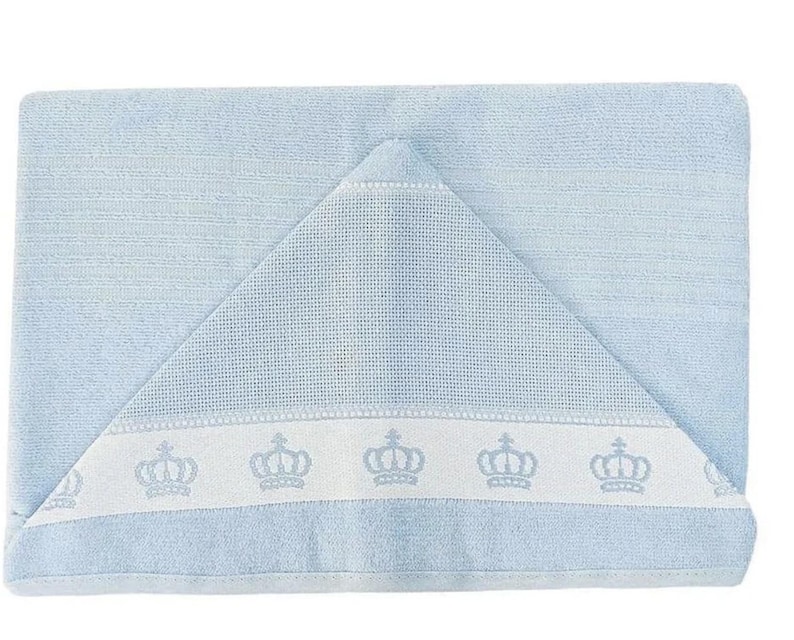 Op de afbeelding: Een lichtblauwe badcape met een witte rand en een rij geborduurde kronen.