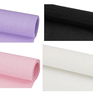 May include: Four rolls of Aida cloth in various colors: lavender, black, pink, and white. The fabric is tightly woven with a grid-like pattern, ideal for cross-stitch and embroidery projects. The rolls are tightly wound.