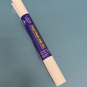 May include: Rolled white vinyl Aida cloth for cross-stitch, with a blue and purple label that reads "Charles Craft Vinyl Aida 13ct". The cloth measures 12 x 18 inches.