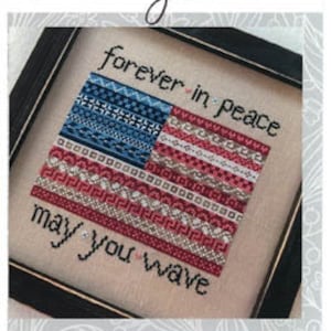 May include: A framed cross-stitch design featuring an American flag with the text "forever in peace may you wave".