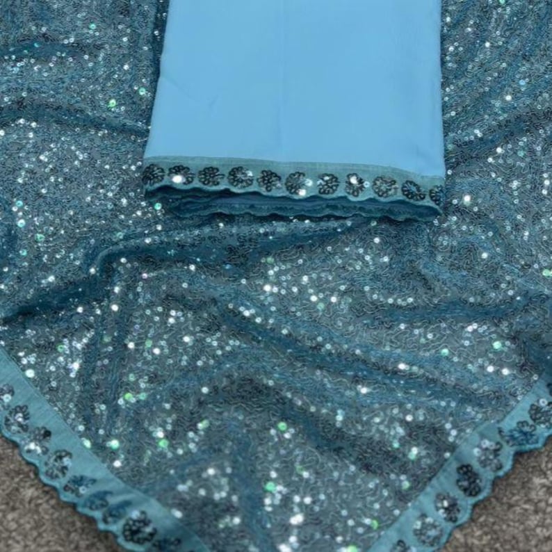 Puede incluir: Una tela de color turquesa con un dise&ntilde;o de lentejuelas y una tela azul claro. La tela turquesa tiene un borde festoneado. La tela azul claro tiene un ribete decorativo. Es probable que las telas formen parte de una prenda.